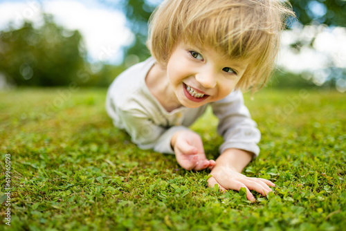Adorable toddler boy having fun outdoors on sunny summer day. Child exploring nature. Summer activities for kids. © MNStudio