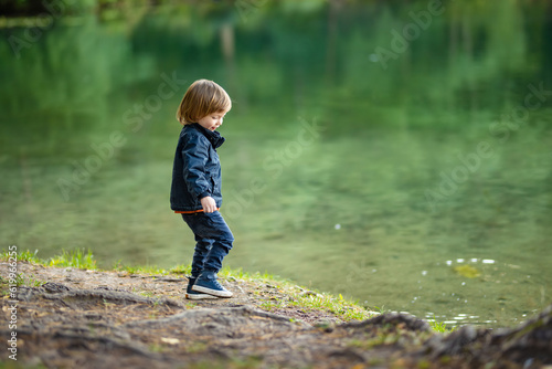 Adorable toddler boy admiring the Balsys lake, one of six Green Lakes, located in Verkiai Regional Park. Child exploring nature on autumn day in Vilnius, Lithuania. photo