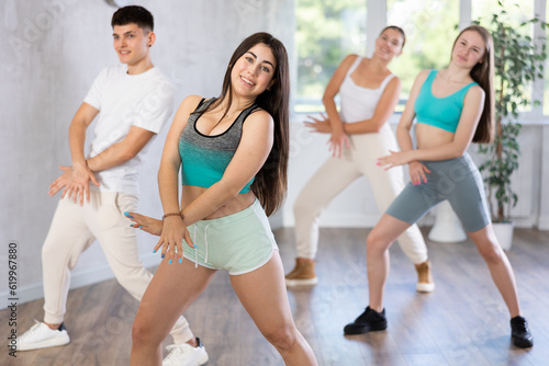 Positive female teenager engage house dance in choreographic school, group of young people in sportswear trains together with their classmates in gym before competitions, battle