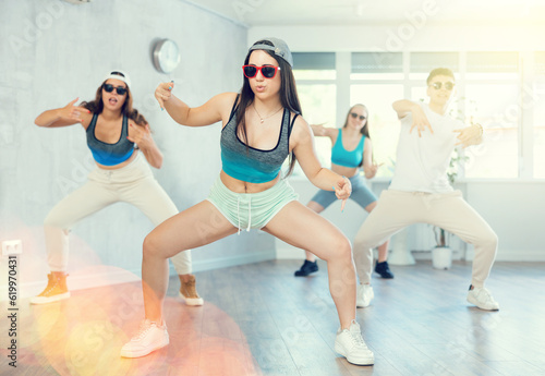 Positive emotional brunette girl performing krump movements with group in modern dance studio.Form of artistic expression of teenagers..
