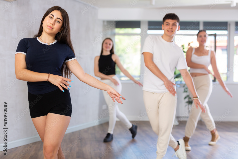 Group of young women and young guy rehearsing contemporary dance in dance studio