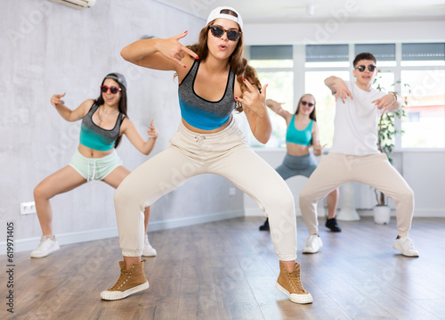 Expressive teenage girl practicing energetic dance movements with group of teens in choreography class
