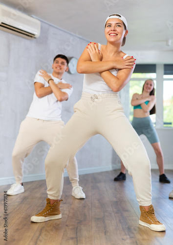 Group of young people learning modern dance movements at class together