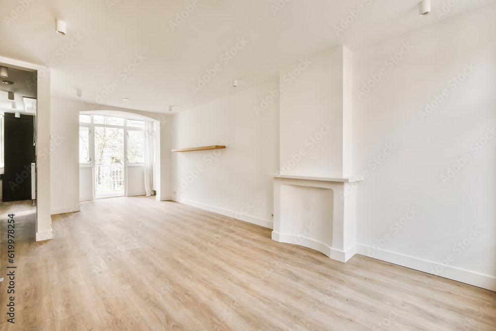 an empty living room with wood flooring and white walls, there is a fireplace in the center of the room an empty living room with wood flooring and white walls, there is a fireplace in the center of the room