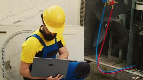 Licensed serviceman using laptop to look online for new evaporator coil after finding external HVAC system malfunctioning internal part during home owner comissioned maintenance