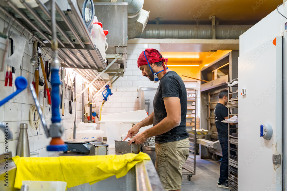 Male baker of bakery in the workshop of artisan bakery preparing the sourdoughs Male baker of bakery in the workshop of artisan bakery preparing the sourdoughs
