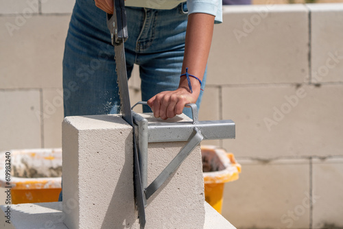 Woman cuts aerated concrete with a masonry saw.