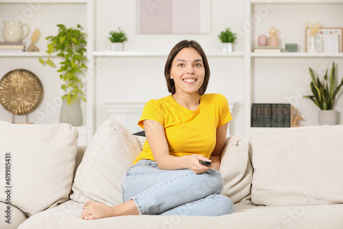 Happy woman watching TV on sofa at home