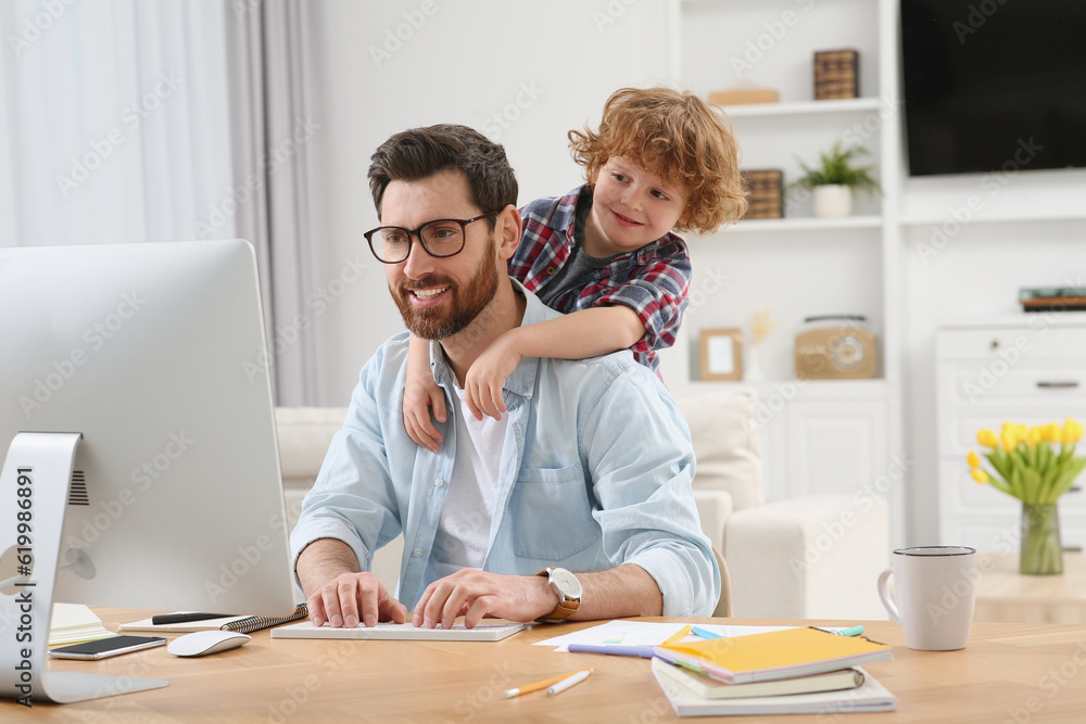 Man working remotely at home. Father with his child at desk