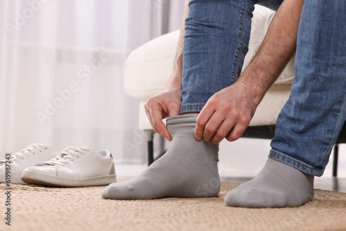 Man putting on grey socks at home  closeup