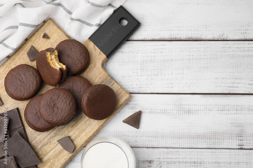 Tasty choco pies and pieces of chocolate on white wooden table, flat lay. Space for text Tasty choco pies and pieces of chocolate on white wooden table, flat lay. Space for text