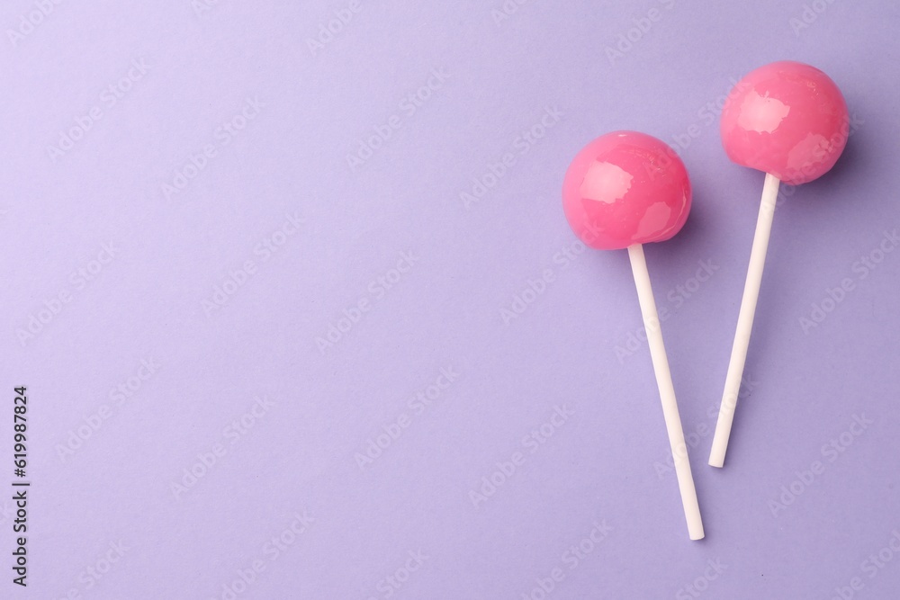 Tasty lollipops on violet background, flat lay. Space for text Tasty lollipops on violet background, flat lay. Space for text