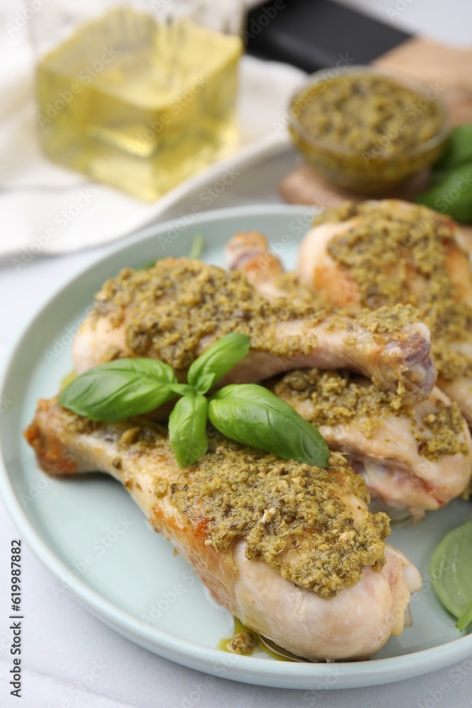 Delicious fried chicken drumsticks with pesto sauce and basil on table