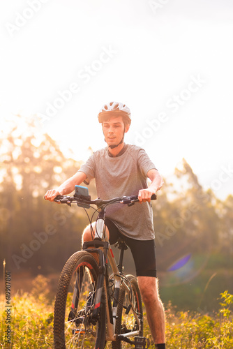 Athlete riding his mountain bike on the trail with sunlight in the background.