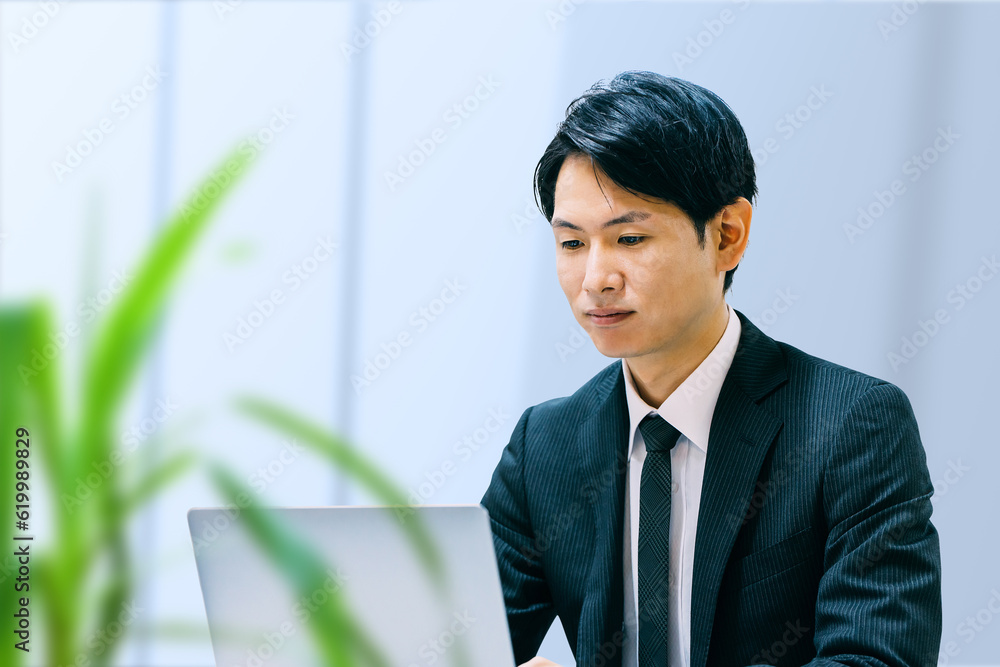 オフィスでノートパソコンを使う日本人ビジネスマン オフィスでノートパソコンを使う日本人ビジネスマン