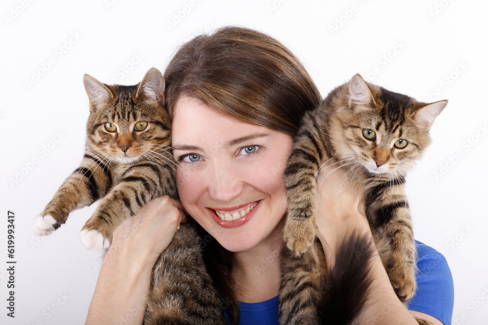 Young woman with domestic cats against white background.