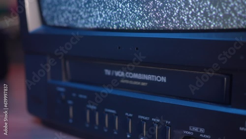 Pushing a VHS Video Cassette Tape Inside the VCR of an Old TV