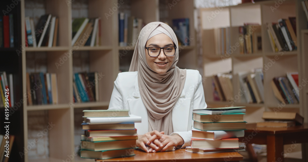 Portrait of female muslim student, wearing hijab, who is at campus library and confidently looking at camera - modern Islam concept Portrait of female muslim student, wearing hijab, who is at campus library and confidently looking at camera - modern Islam concept