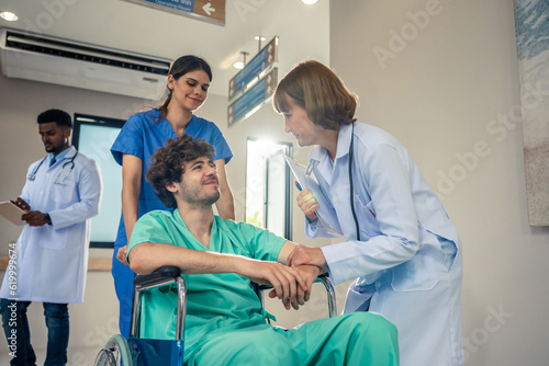 Caucasian doctor support patient sit on wheelchair in hospital hallway. 