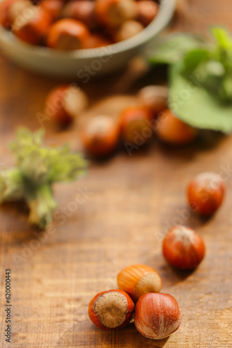 Hazelnuts in a green cup.Nut Harvest Season. nuts in a cup on a wooden table.Nuts with green leaves.