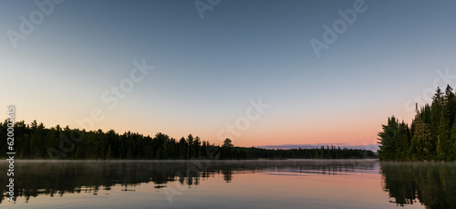 a lake in northern Canada at dust with a gradient sky from blue to pink 