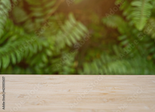 Wooden table top with blurred green leaves behind with orange sunlight