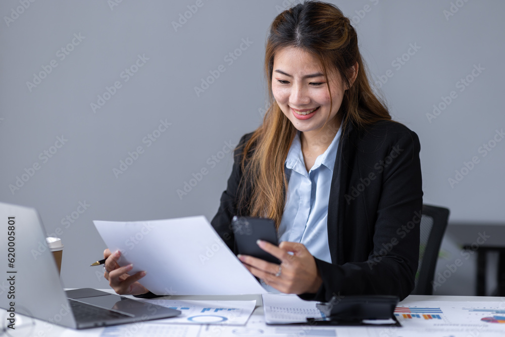 Thoughtful young asian woman entrepreneur holding smart phone and checking financial reports business plan investment, finance analysis concept Thoughtful young asian woman entrepreneur holding smart phone and checking financial reports business plan investment, finance analysis concept