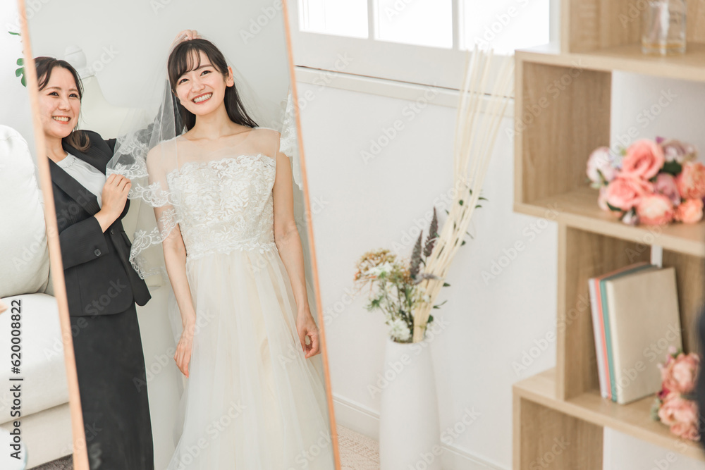 Fototapeta premium 鏡を見ながら結婚式のウェディングドレス・ベールの衣装合わせ・試着をする花嫁