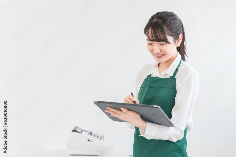 コンビニ・スーパーでタブレット端末を使って在庫管理・棚卸しをする店員・バイトの女性
