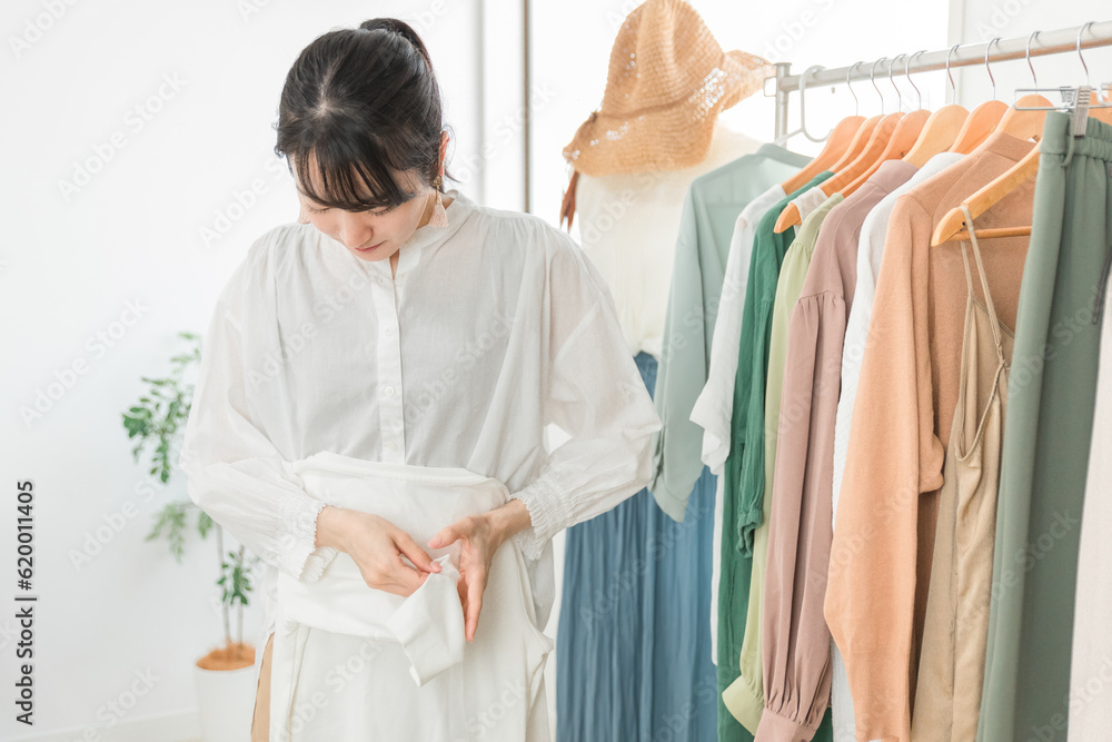 Obraz premium 服を畳むショップ・服屋で働く販売員・従業員・ショップ店員のアジア人女性 