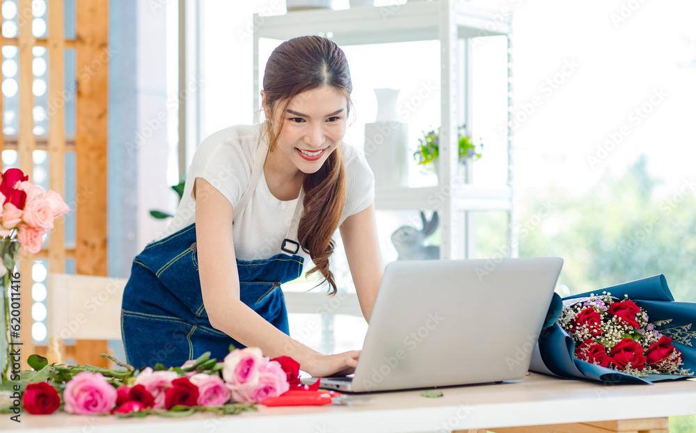 Asian professional successful female florist designer shop owner entrepreneur businesswoman in apron working order using laptop notebook computer open floral garden store studio Asian professional successful female florist designer shop owner entrepreneur businesswoman in apron working order using laptop notebook computer open floral garden store studio