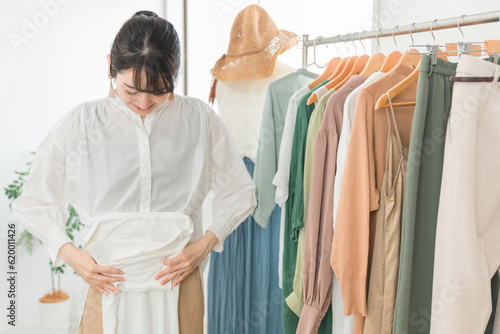 服を畳むショップ・服屋で働く販売員・従業員・ショップ店員のアジア人女性 