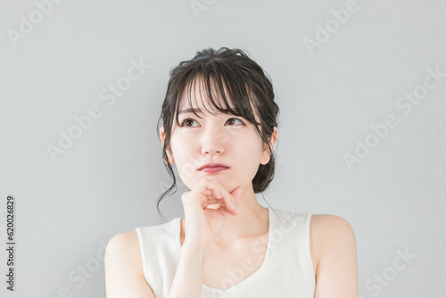 頬杖をついて考える・悩むアジア人女性（美容・ダイエット・エステ・脱毛）
 photo