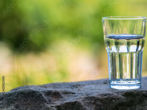 a glass of water on stone in nature with blurred background MADE OF AI