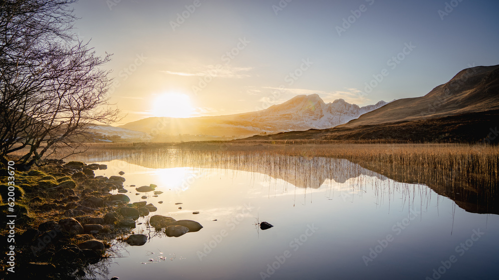 Winter sunset of Bla Bheinn (Blavin) mountain in Isle of Skye, Scotland, with a reflection on a still lake.