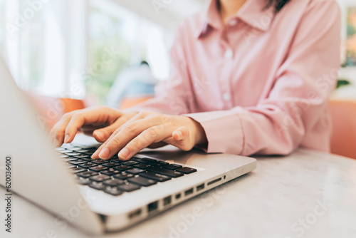 Foto A freelancer is sitting in a café, using a laptop to reply to clients' inquiries and requests