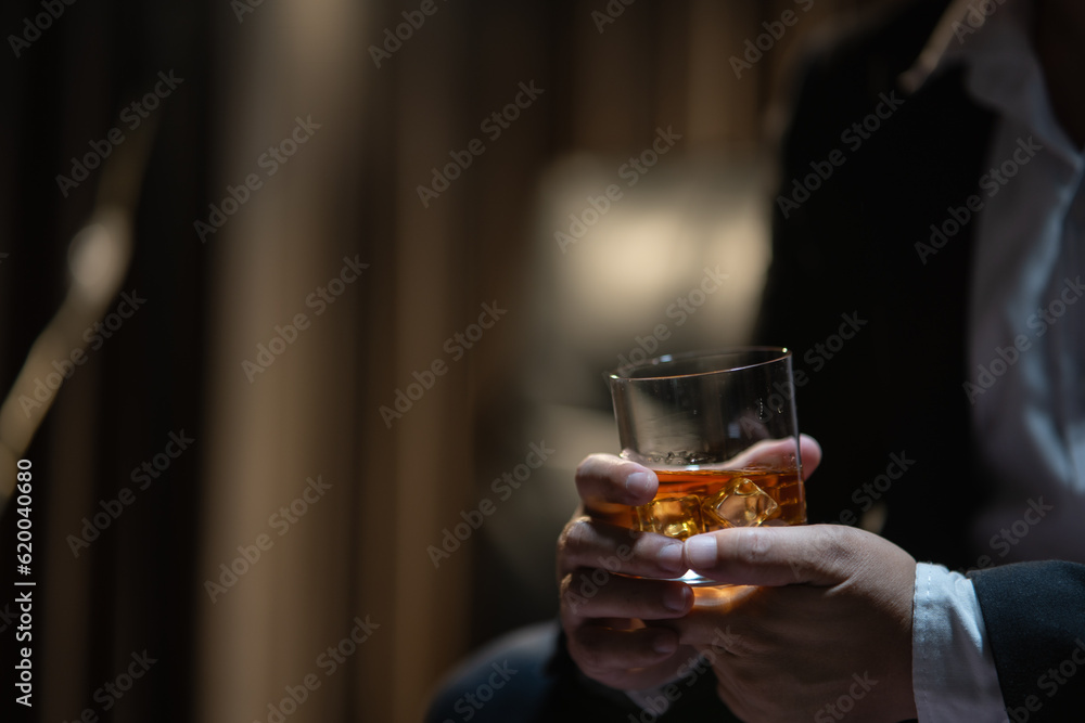 Businessman sitting Holding a Glass of Whiskey Drink Whiskey in the liquor store room Businessman sitting Holding a Glass of Whiskey Drink Whiskey in the liquor store room