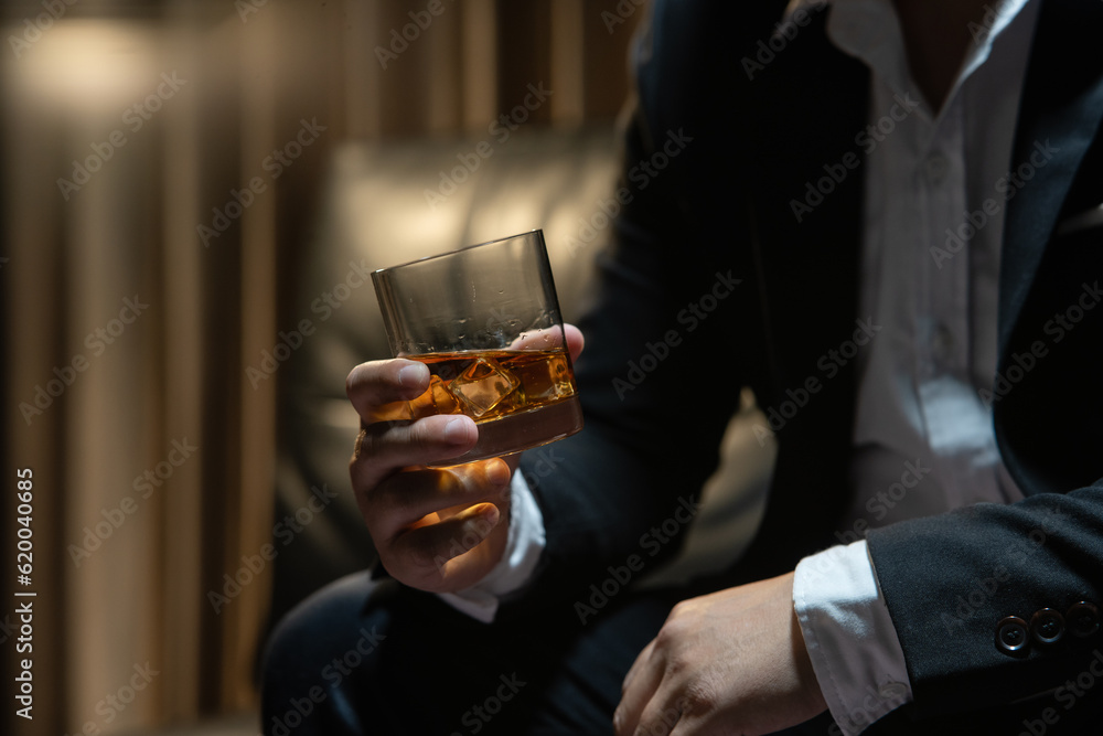 Businessman sitting Holding a Glass of Whiskey Drink Whiskey in the liquor store room