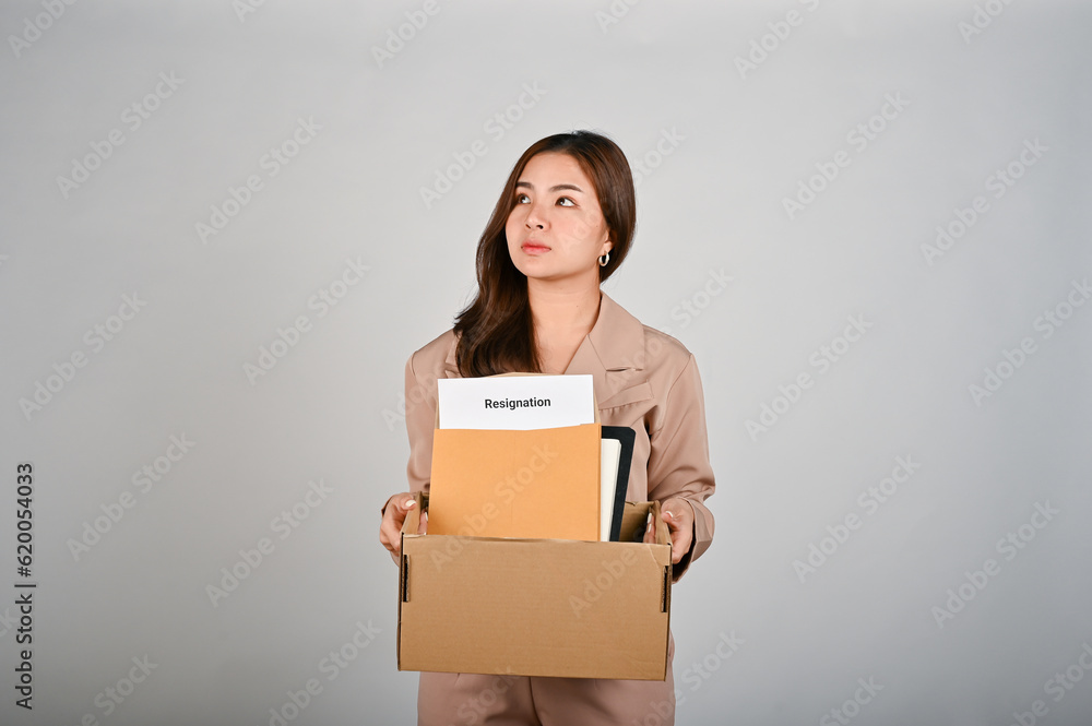 Sad young businesswoman holding a box full of her stuff, feeling sad after quitting her job Sad young businesswoman holding a box full of her stuff, feeling sad after quitting her job