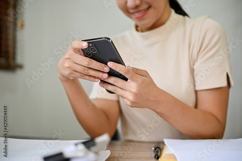 Close up view of young beautiful woman using smartphone at her desk