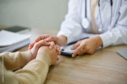 Close up view of doctor touching patient hand, showing empty and kindness. photo
