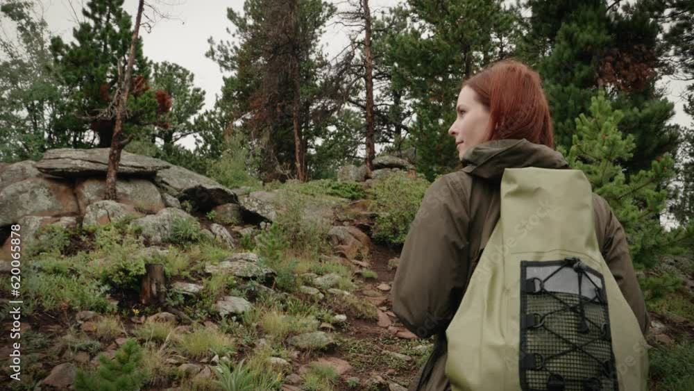 A girl backpacker hikes through a green forest. She looks over and smiles. A girl backpacker hikes through a green forest. She looks over and smiles.
