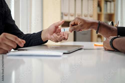 Hands of developer giving USB flash drive with importtant data to colleague