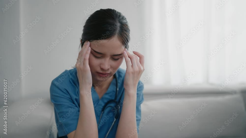 Tired depressed young asian woman nurse in uniform suffer from headache after hard working. Exhausted sad woman doctor feels burnout stress. Physician burnout Tired depressed young asian woman nurse in uniform suffer from headache after hard working. Exhausted sad woman doctor feels burnout stress. Physician burnout
