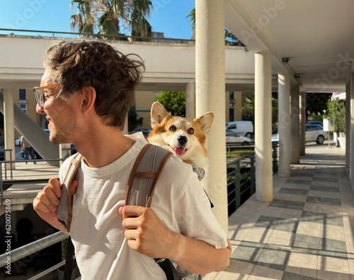 Fotografia Man travelling with his dog in a backpack. Vacation with a pet