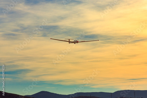 Glider approach for landing against the backdrop of mountains at sunset.