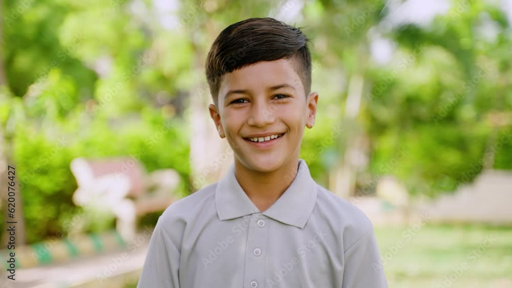 Happy smiling indian boy kid looking at camera at park - concept of - concept of Playful Expression, Outdoor Happiness and Joyful Child