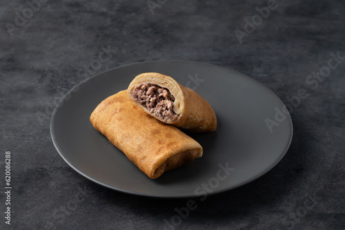 Delicious crepes roll with meat pork or beef on a plate on a dark  isolated background. Concept of healthy homemade food for the breakfast.