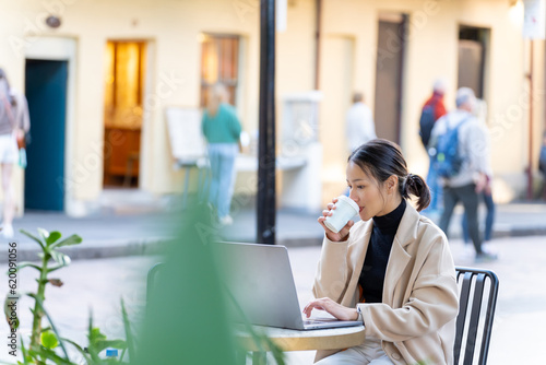 Canvas Print Young Asian woman freelance enjoy working business or creative job on laptop computer at outdoor cafe in the city