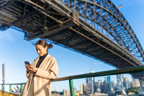 Obraz na płótnie Asian woman using mobile phone during travel on ferry boat crossing harbor in Sydney, Australia